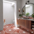 Bathroom with wooden vanity, round mirror, and patterned red and white floor.
