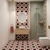 Modern bathroom with red patterned tiles, wooden vanity, and glass shower enclosure.